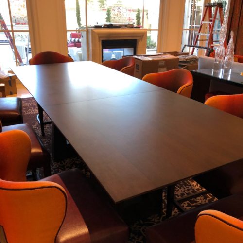 A long table with orange chairs around it