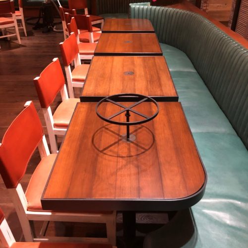 A restaurant booth with four chairs and one bench.