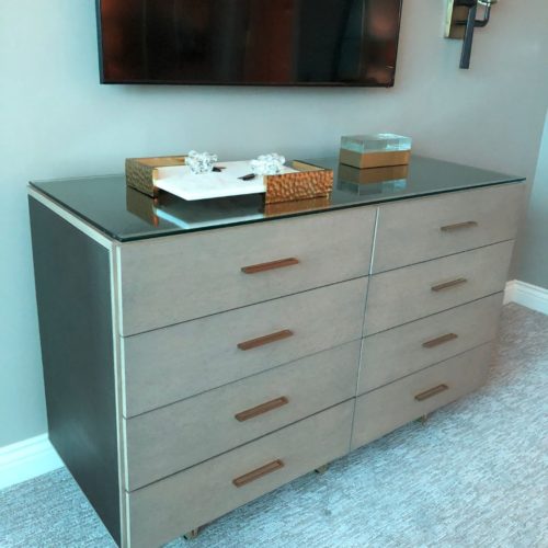 A dresser with six drawers and glass top.