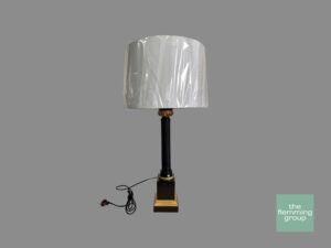 A lamp with a white shade sitting on top of it.