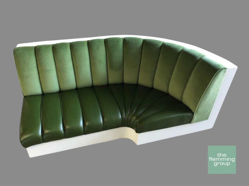 A green leather couch with white trim and the seat is curved.