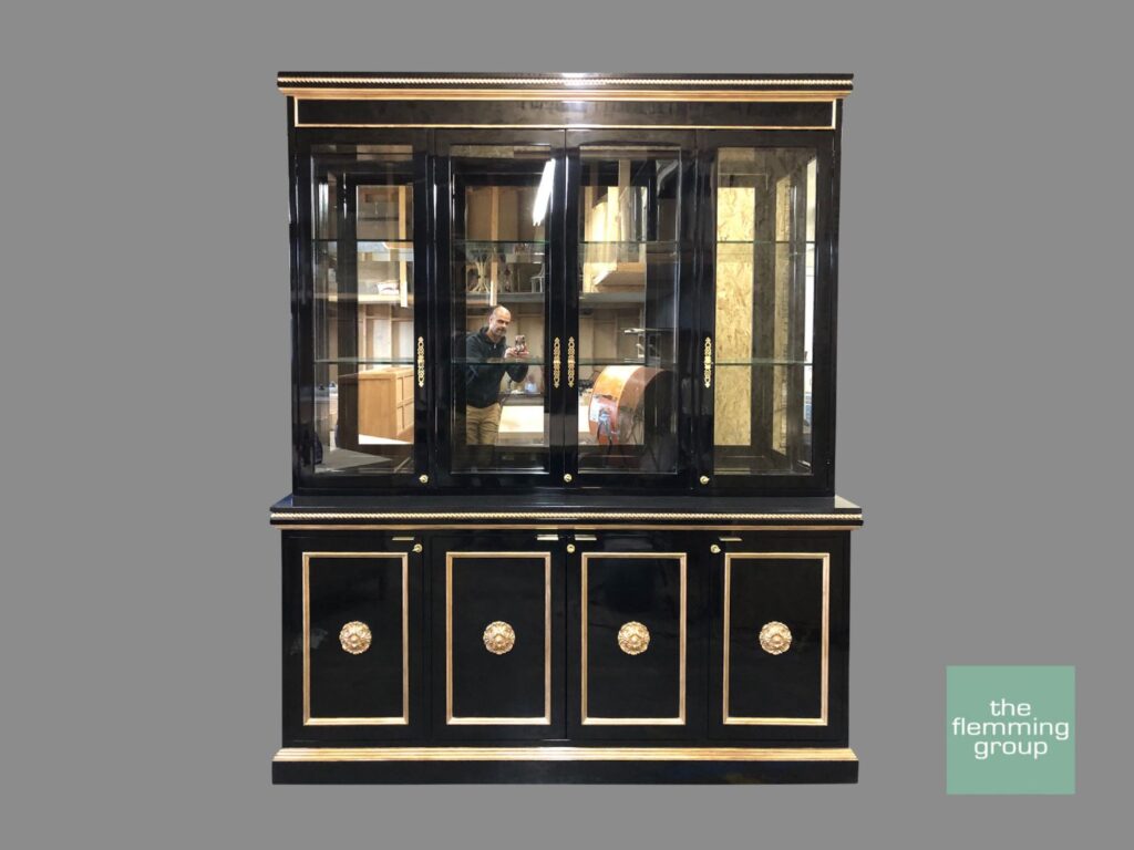 A black and gold china cabinet with four glass doors.