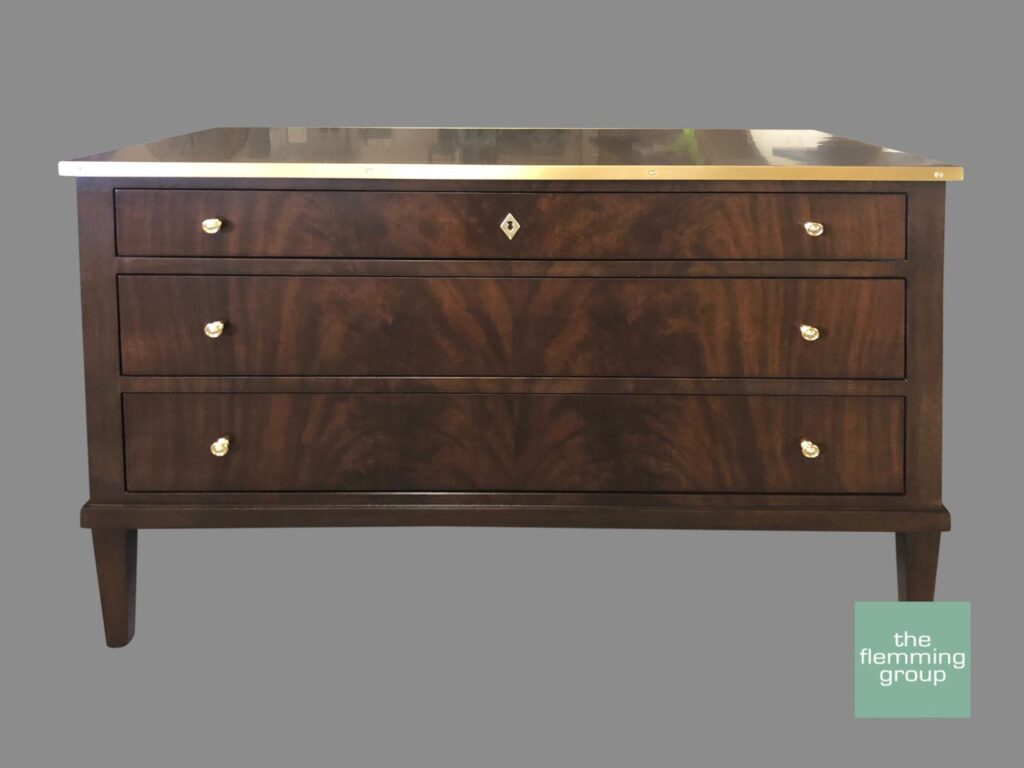 A wooden dresser with three drawers and gold handles.