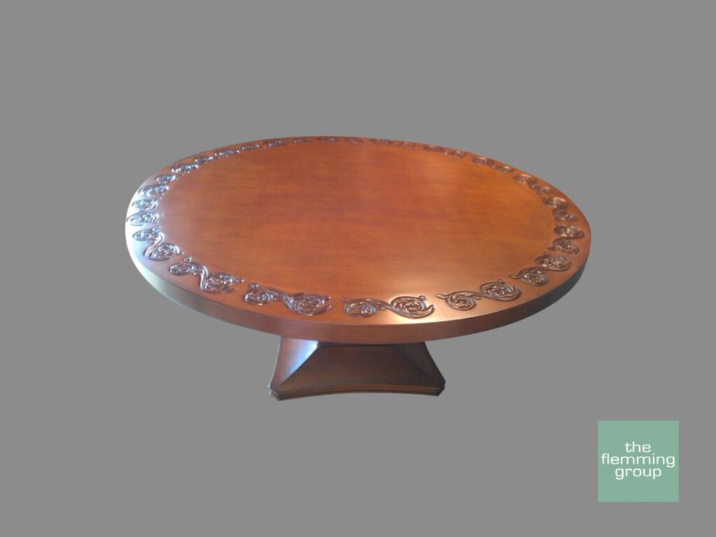 A wooden table with a round top and decorative design.