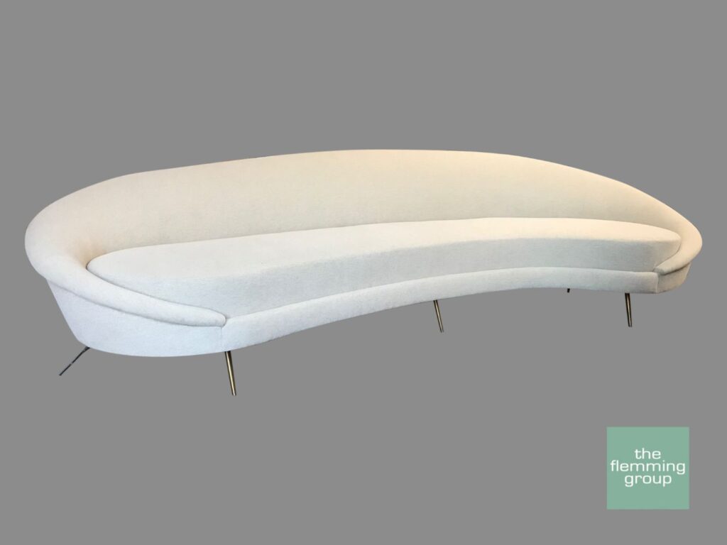 A white couch with metal legs on top of it.