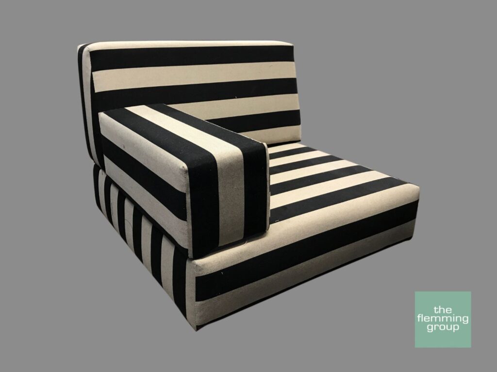 A black and white striped chair with a corner cushion.