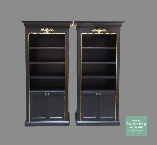 A pair of black bookcases with gold trim.