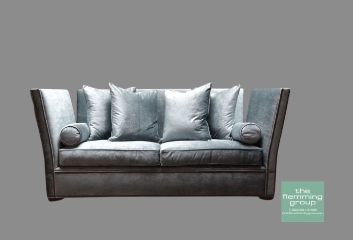 A couch with pillows on it in front of a gray background.