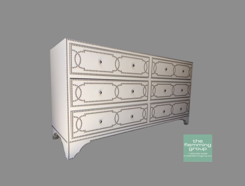 A white dresser with six drawers and a silver trim.